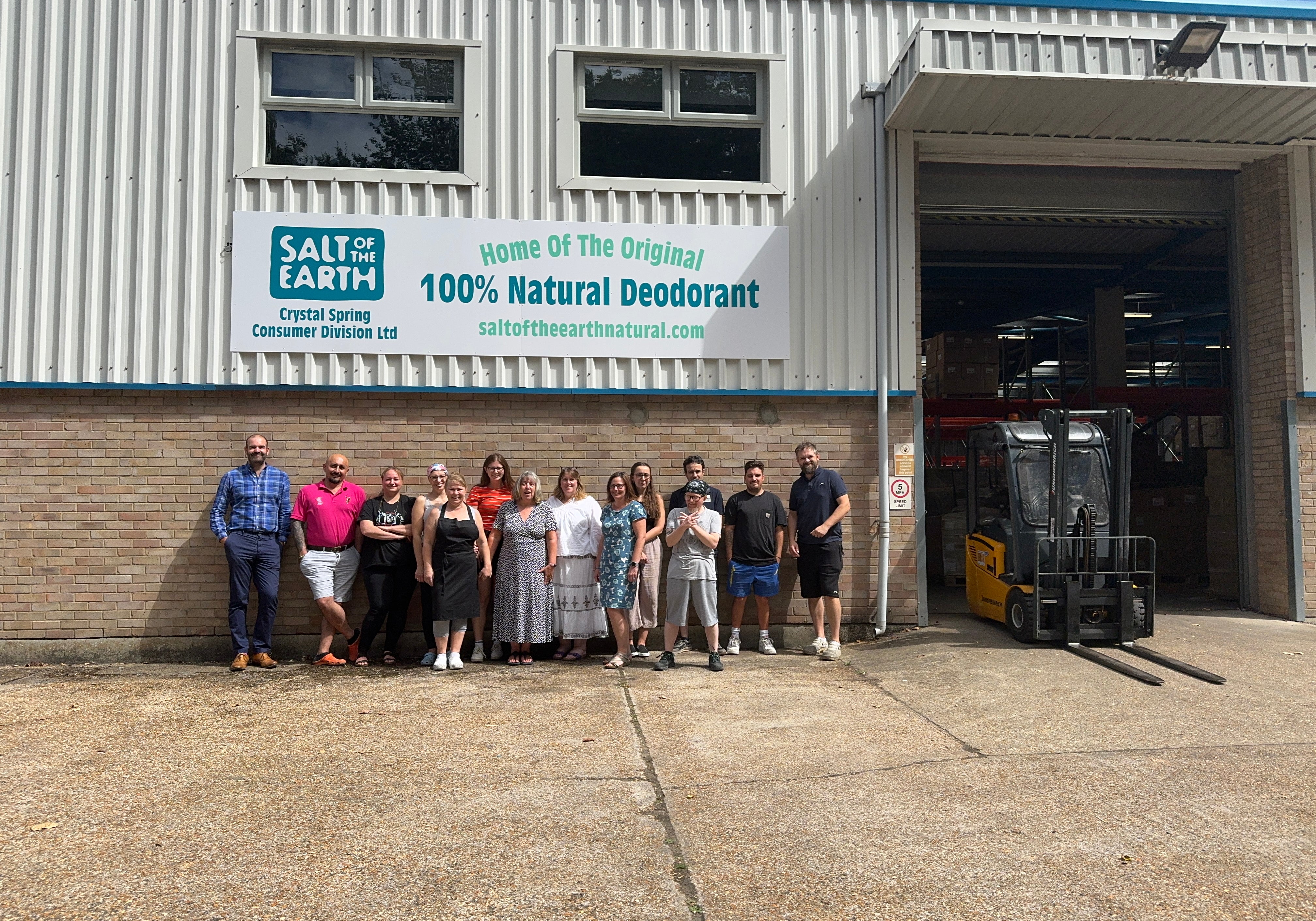 Salt of the Earth team standing proudly outside their warehouse, showcasing teamwork and authenticity in a spontaneous, unedited group photo in front of a roll shutter door.