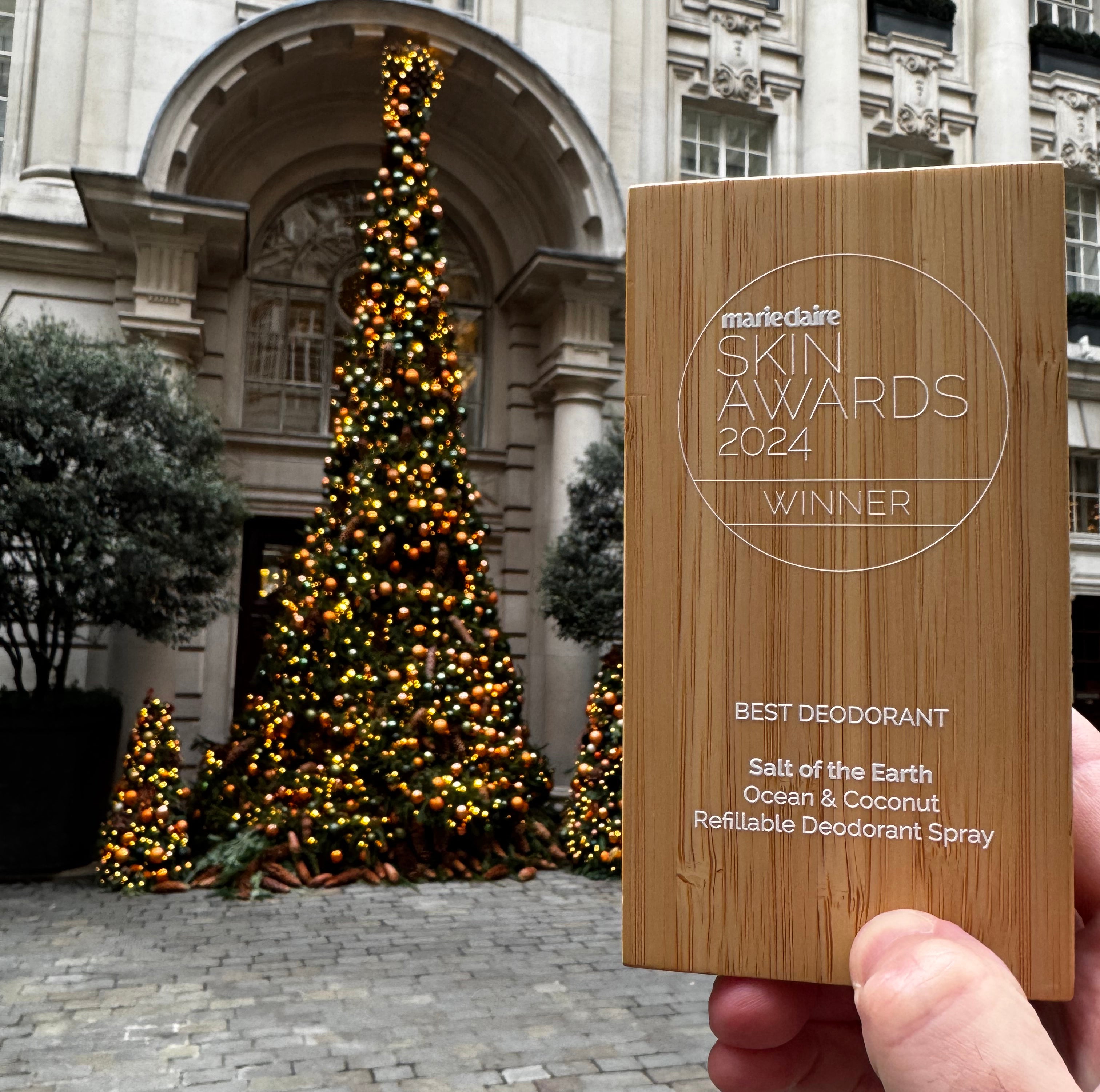 Marie Claire Beauty Award 2024 held against a decorated Christmas tree, celebrating Ocean & Coconut Spray Deodorant's win